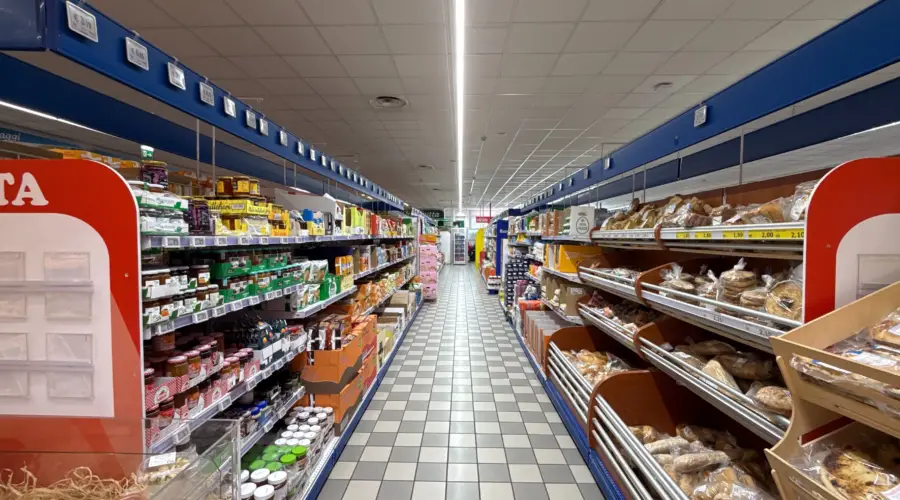 Corsia di supermercato illuminata con impianto LED professionale che valorizza i prodotti e migliora il comfort visivo dei clienti.